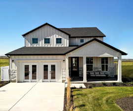 View of front of home with covered porch, french doors, and a front lawn