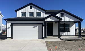 Modern inspired farmhouse with a garage, concrete driveway, board and batten siding, and roof with shingles