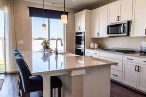 Kitchen with sink, stainless steel appliances, a center island with sink, and pendant lighting