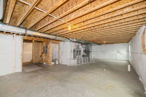 Basement featuring electric panel, heating unit, and water heater