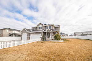 View of front facade featuring solar panels, a front yard, and a garage