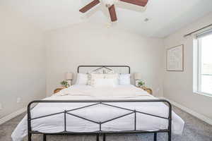 Bedroom featuring ceiling fan, multiple windows, carpet, and lofted ceiling