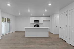 Kitchen with a center island with sink, laminate flooring, white cabinets, appliances with stainless steel finishes, and sink