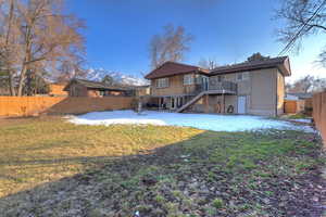 Rear view of house featuring a deck with mountain view and a lawn