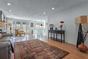 Living room featuring a textured ceiling, light hardwood / wood-style flooring, and french doors