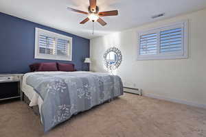 Bedroom with light carpet, a baseboard heating unit, and ceiling fan