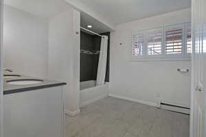 Bathroom with a baseboard radiator, shower / bath combo, and vanity