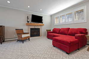 Living room featuring a tile fireplace, crown molding, and a baseboard heating unit