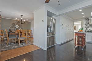 Dining area with a notable chandelier, crown molding, and dark hardwood / wood-style flooring