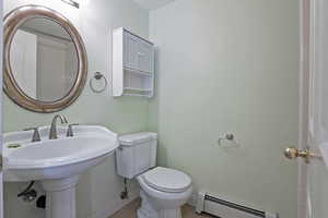 Bathroom with toilet, baseboard heating, hardwood / wood-style flooring, and sink