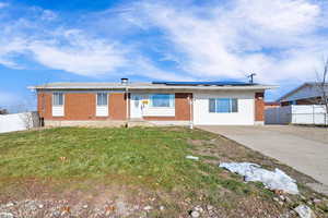 Ranch-style house featuring solar panels and a front lawn