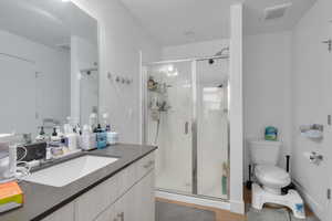 Bathroom featuring toilet, hardwood / wood-style floors, walk in shower, and vanity