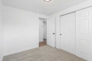 Unfurnished bedroom with a closet and light carpet