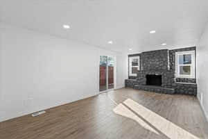 Unfurnished living room with hardwood / wood-style floors and a stone fireplace