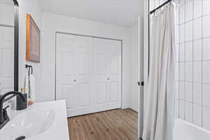 Bathroom with shower / bathtub combination with curtain, hardwood / wood-style floors, and vanity