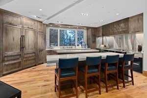 Kitchen featuring light wood-type flooring, a center island, a breakfast bar area, and dark brown cabinetry