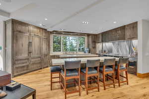 Kitchen featuring light wood-style flooring, light countertops, a kitchen breakfast bar, a spacious island, and recessed lighting