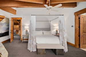 Carpeted bedroom featuring ceiling fan and beam ceiling