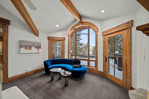 Living area with ceiling fan, vaulted ceiling with beams, and carpet