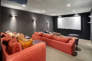 Home theater room featuring a textured ceiling and carpet flooring