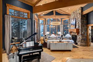 Interior space featuring beam ceiling, wood ceiling, a stone fireplace, and a chandelier