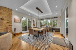 Dining room with a raised ceiling, light wood finished floors, and recessed lighting
