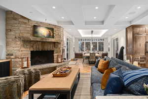 Living room featuring a tray ceiling, light hardwood / wood-style flooring, and a stone fireplace