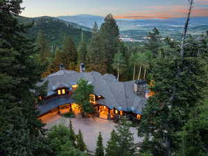 Aerial view of property and surrounding area with a mountain backdrop and a forest