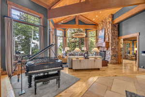 Living area with a wood ceiling with exposed beams, high vaulted ceiling, a chandelier, and wood finished floors