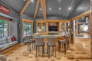 Indoor wet bar featuring beamed ceiling, light wood-style flooring, recessed lighting, and high vaulted ceiling
