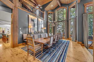Dining area featuring high vaulted ceiling, hardwood / wood-style floors, a chandelier, and a wood ceiling with exposed beams