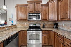 Kitchen with light stone countertops, stainless steel appliances, and decorative backsplash