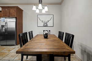 Dining area with crown molding and a chandelier