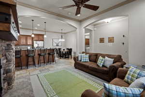 Living room featuring crown molding and ceiling fan with notable chandelier