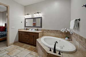 Bathroom featuring tiled tub and vanity