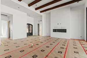 Unfurnished living room featuring beamed ceiling