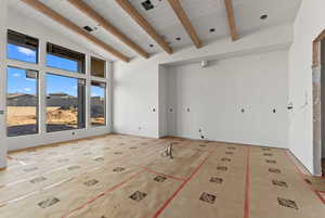 Unfurnished room with high vaulted ceiling and beam ceiling