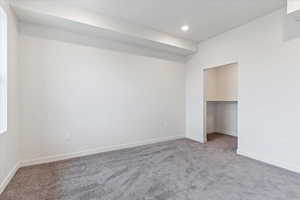 Unfurnished bedroom featuring carpet floors, a closet, and a spacious closet