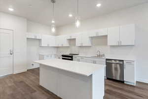 Kitchen featuring stainless steel dishwasher, hanging light fixtures, electric range, white cabinets, and sink