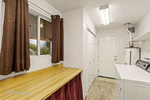 Laundry area featuring washer and dryer, light colored carpet, water heater, and a textured ceiling