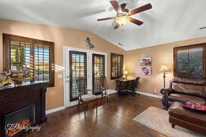 Living room with vaulted ceiling, ceiling fan, and dark hardwood / wood-style floors