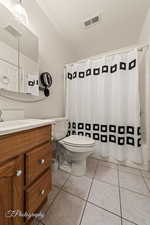 Full bathroom with a textured ceiling, tile patterned flooring, toilet, shower / bath combination with curtain, and vanity