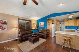 Living room with ceiling fan, lofted ceiling, and dark hardwood / wood-style floors