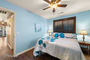 Bedroom with multiple windows, ceiling fan, and dark hardwood / wood-style floors