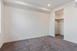 Unfurnished bedroom featuring a closet, a spacious closet, and carpet