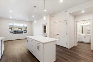 Kitchen featuring a kitchen island, decorative light fixtures, white cabinetry, and dark hardwood / wood-style flooring