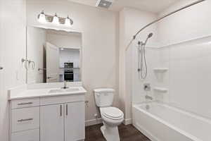 Full bathroom featuring toilet, vanity, hardwood / wood-style flooring, and washtub / shower combination