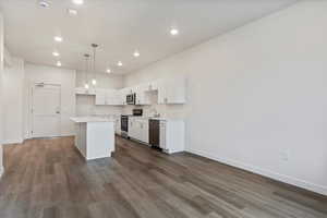 Kitchen featuring stainless steel appliances, sink, white cabinets, a kitchen island, and pendant lighting