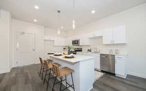 Kitchen featuring white cabinets, dark wood-type flooring, stainless steel appliances, and a center island