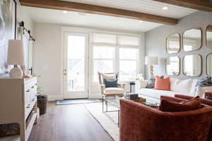 Living room with V-grooving and beamed ceiling, hardwood / wood-style flooring, and  wallpaper